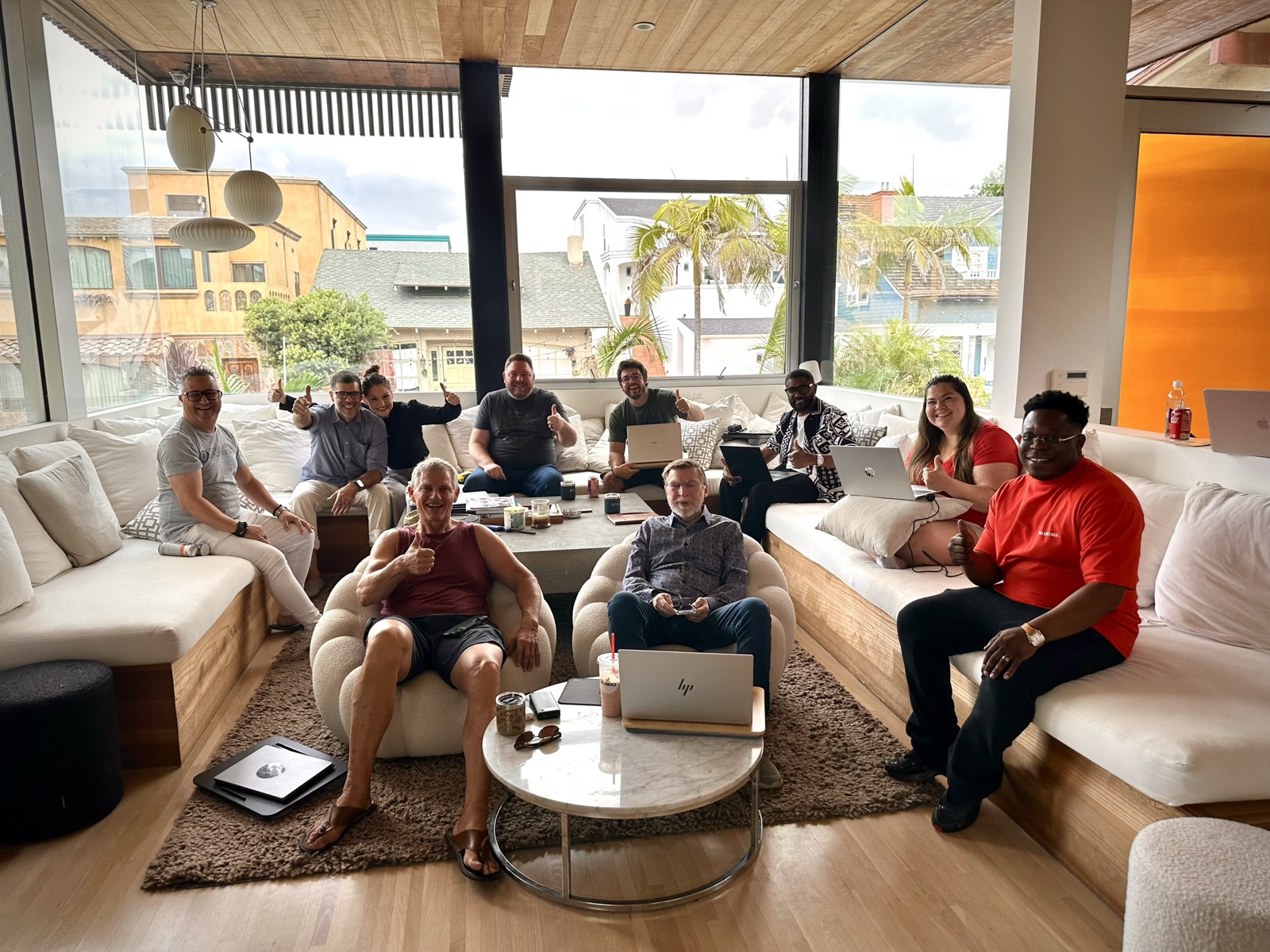 Claude Bootcamp attendees on the sofas with their laptops, giving a thumbs up